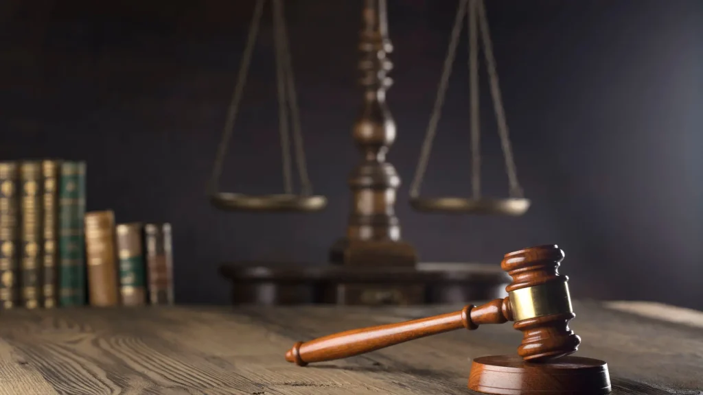 Gavel on a wooden desk with scales of justice in the background.