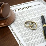 Divorce papers with wedding rings and a gavel.