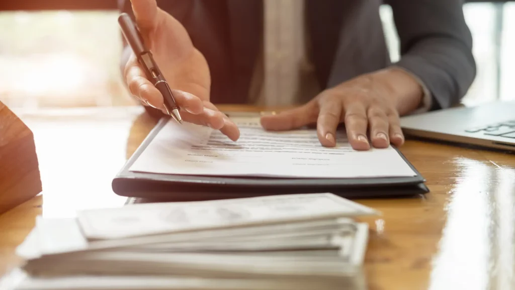 Hand signing legal document on clipboard